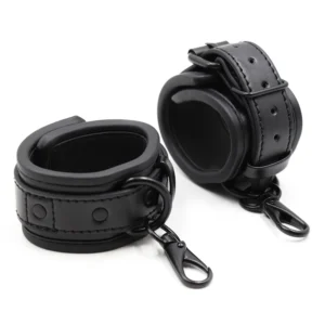 Close-up of black adjustable leather handcuffs with silver metal buckles for BDSM bondage.