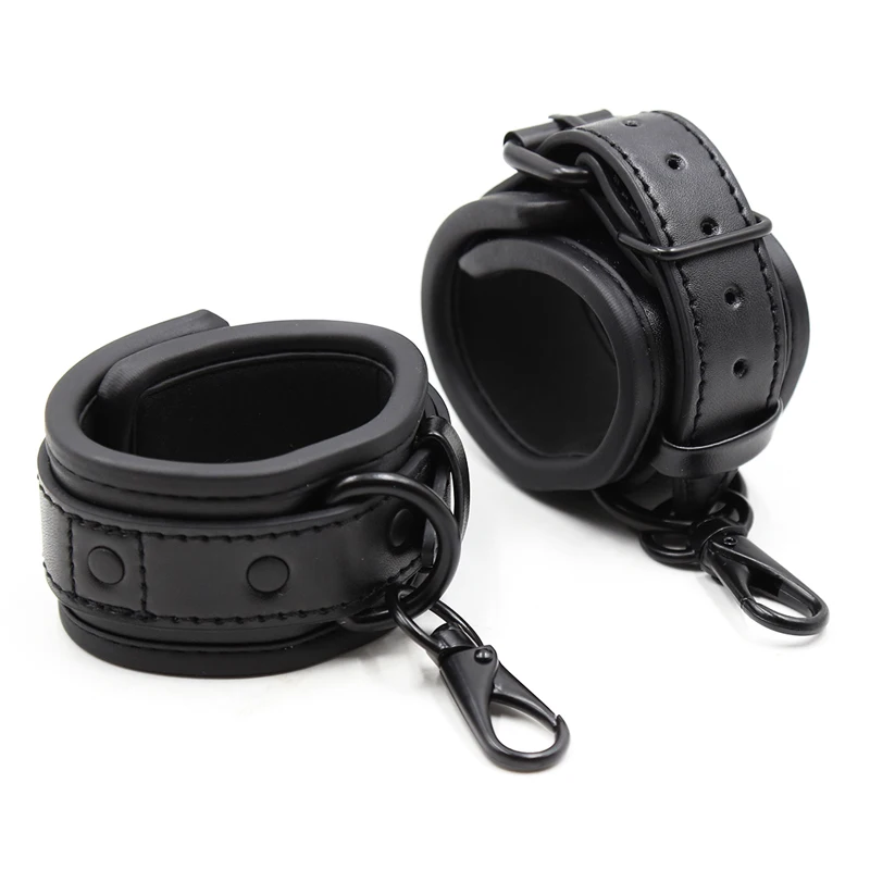 Close-up of black adjustable leather handcuffs with silver metal buckles for BDSM bondage.