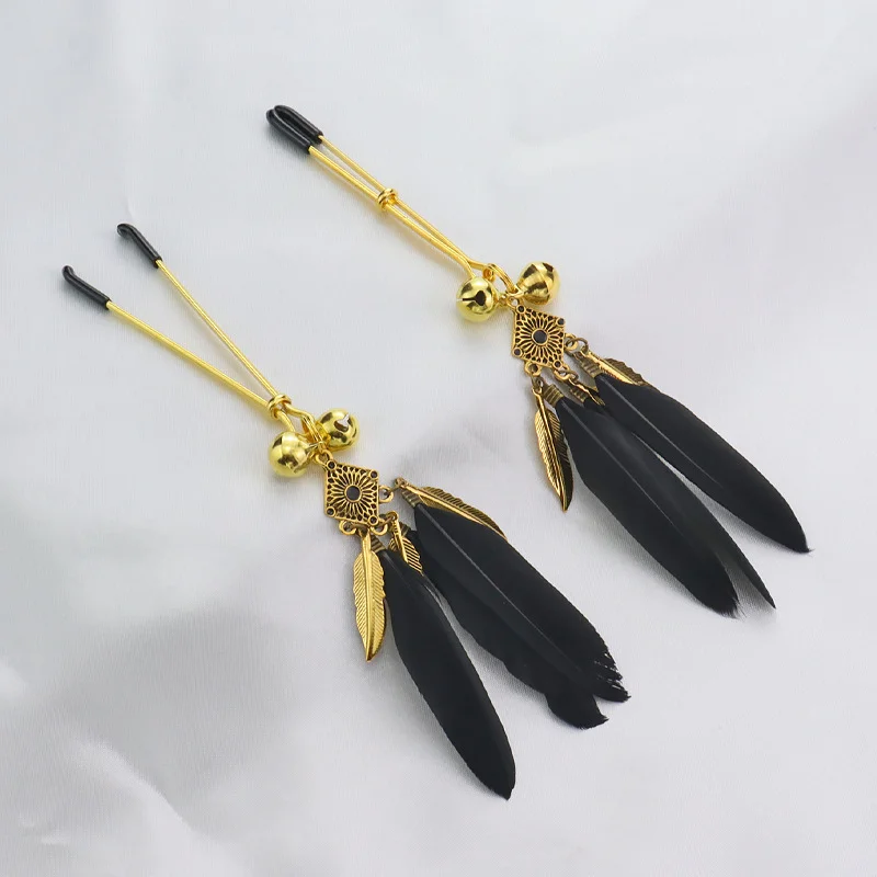 Pair of silver metal nipple clamps featuring white feather charms and small circular bells for sensory SM teasing play.