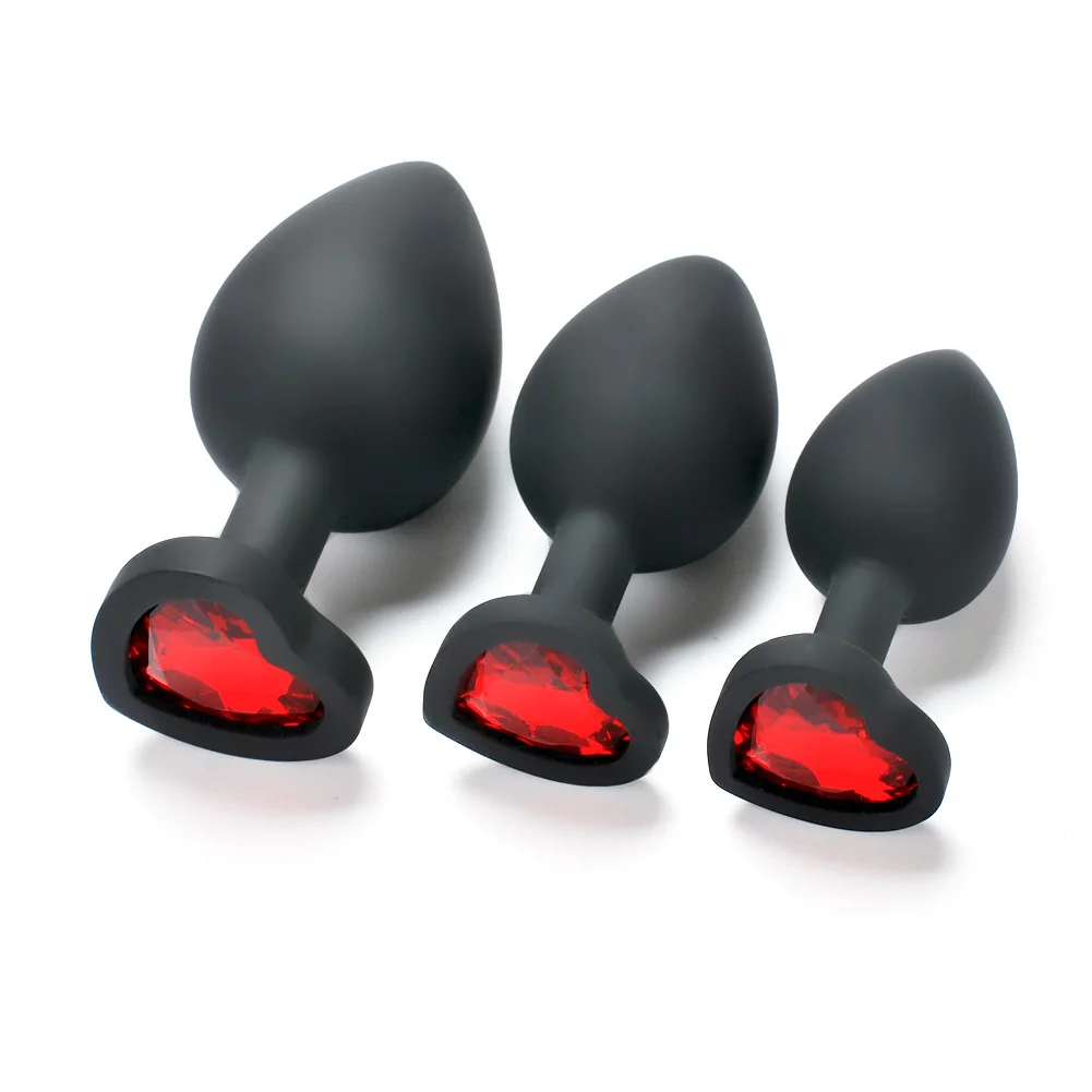 Three different sized black silicone anal plugs with sparkling crystal heart-shaped bases arranged in a row.