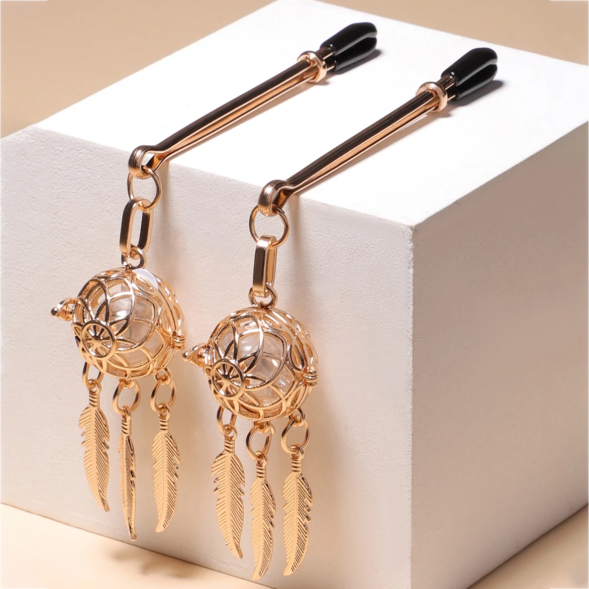 Silver-tone metal nipple clamps with red silk tassels and small decorative bells for BDSM play.
