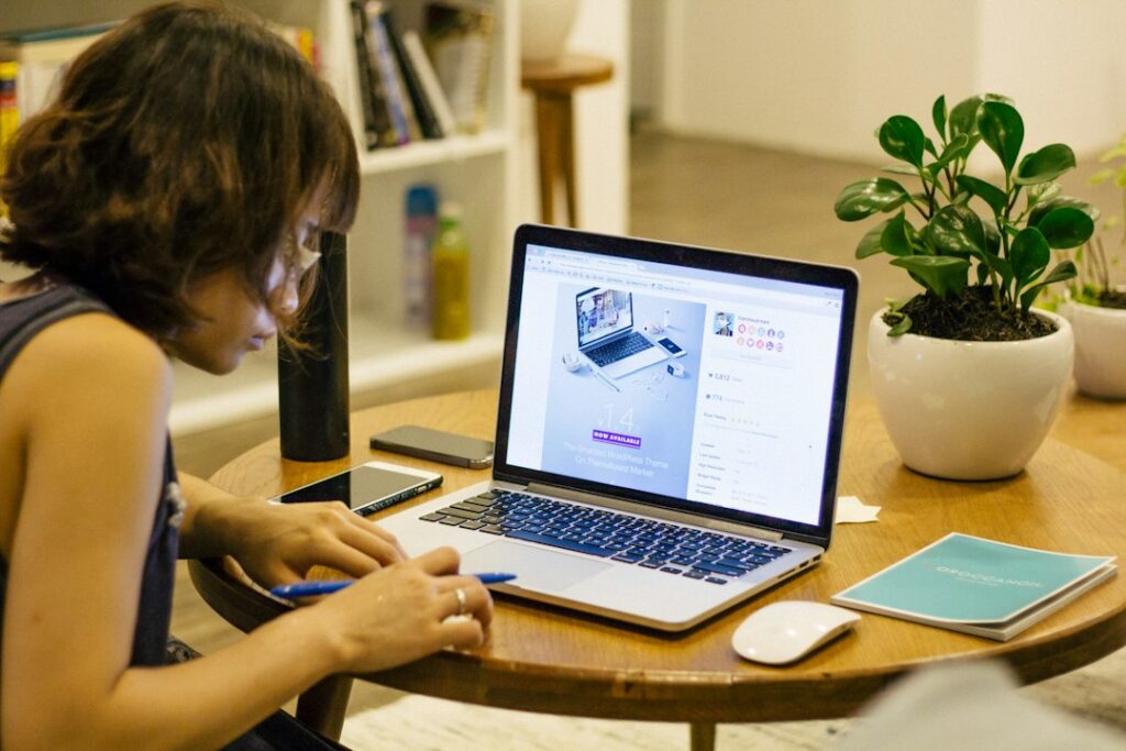 Person studying at a laptop at home, taking notes while learning online with flexible AI-assisted education tools