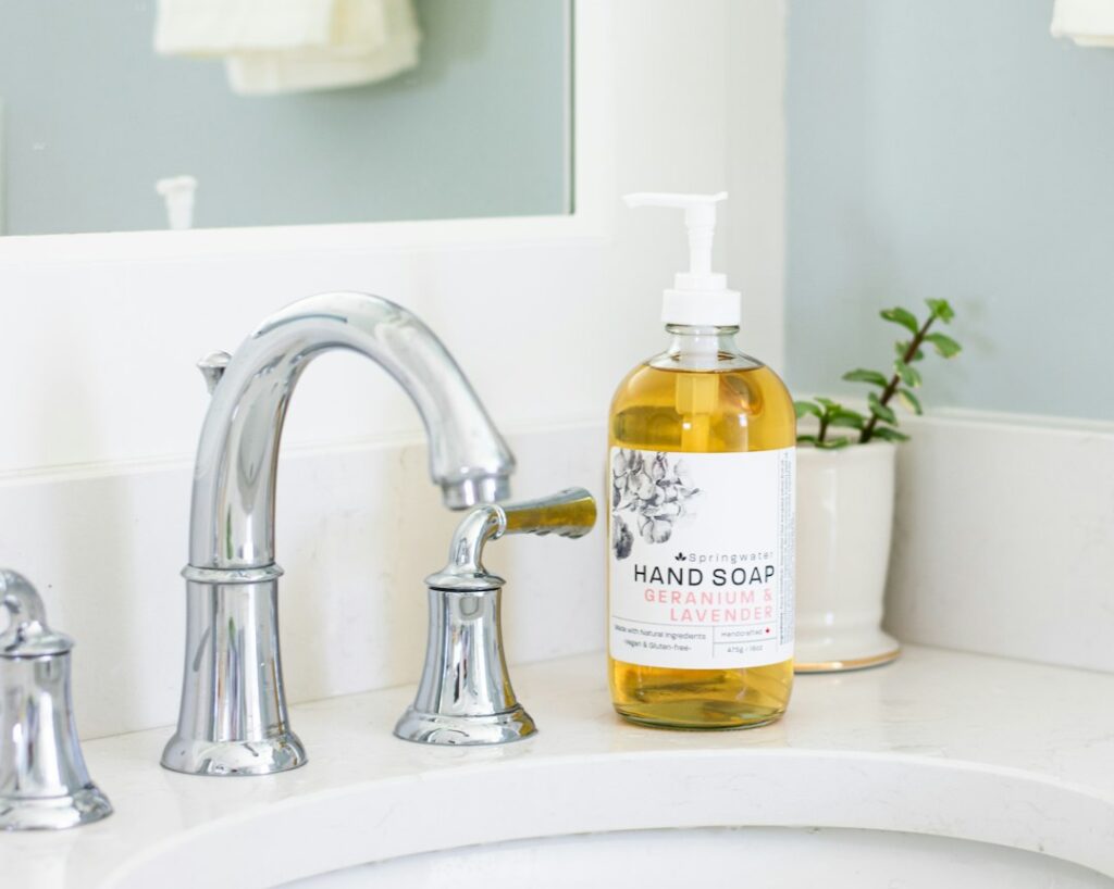 Elegant liquid hand soap pump bottle next to a bathroom sink, representing proper toy cleaning with mild unscented soap and warm water